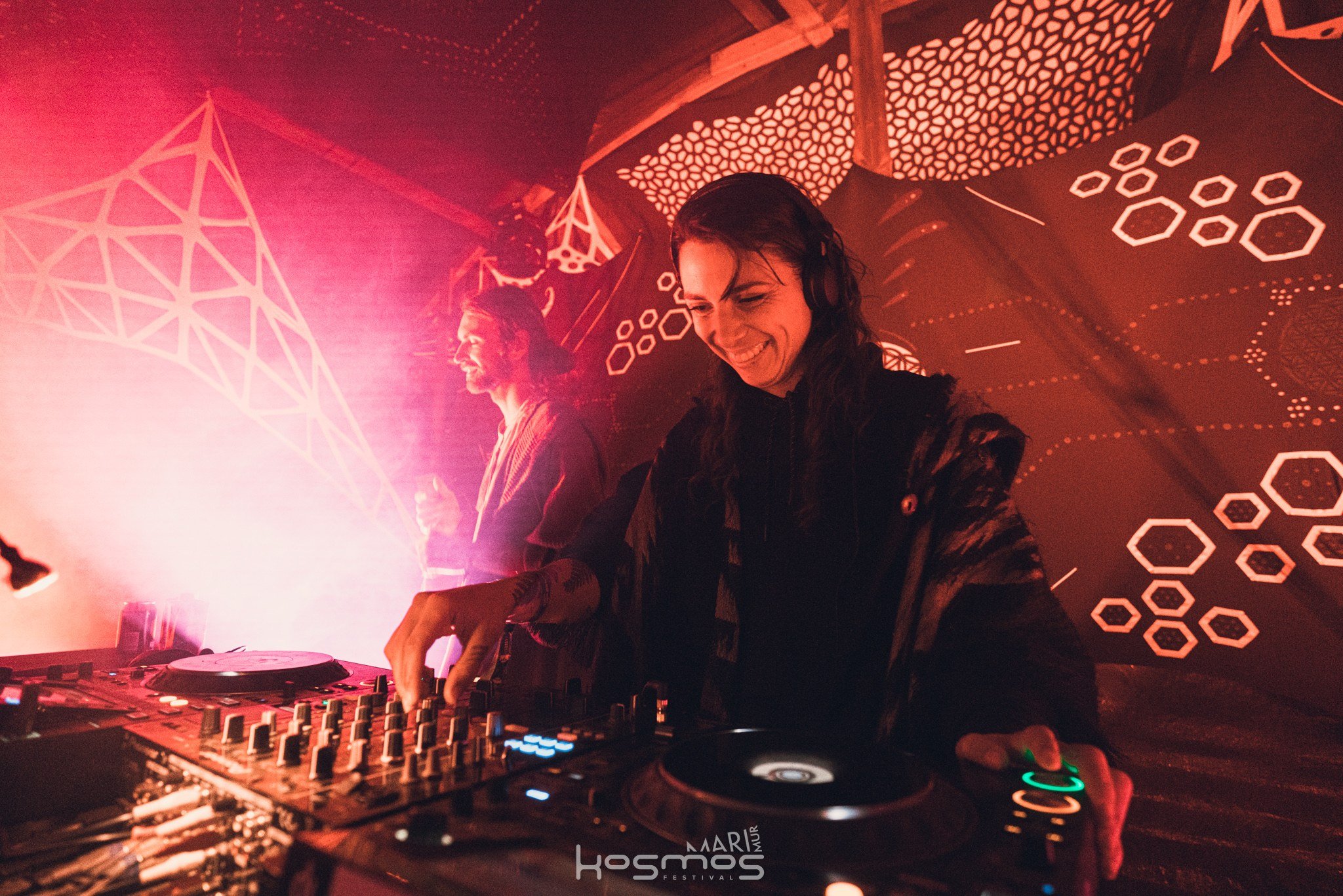 A photo of Safira playing music on a DJ mixer, with a big smile.